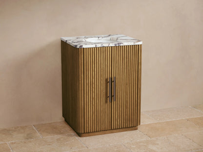 Finnley Powder Vanity: Warm oak wood with fluted doors, white marble top with grey veining, oval sink, and dark bronze faucet.