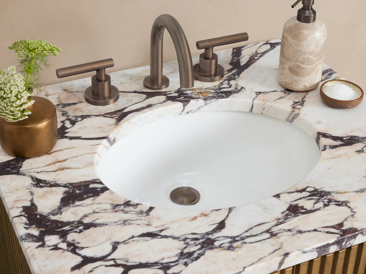 Finnley Powder Vanity with fluted light oak cabinet, white veined marble top, oval sink, and dark vertical handles.