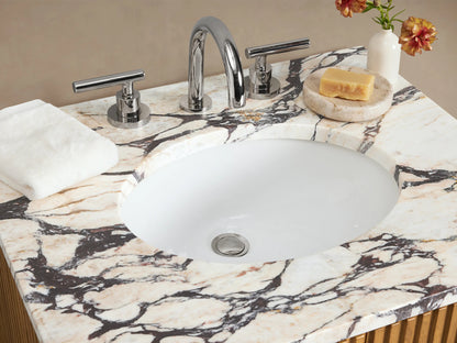 Finnley Powder Vanity: light oak wood, reeded doors, silver handles, white marble top with sink, set in a beige room.