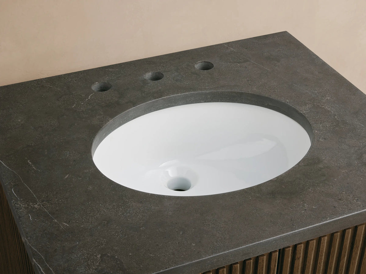 Close-up Finnley Powder Vanity with dark gray stone top, white oval sink, chrome faucet, and ribbed wood cabinet.