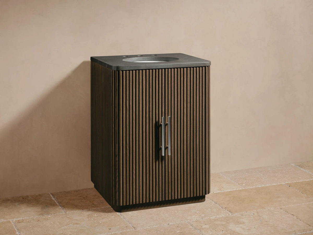 Finnley Powder Vanity with dark brown fluted wood cabinet, gray stone top, oval sink, and silver faucet/handles.