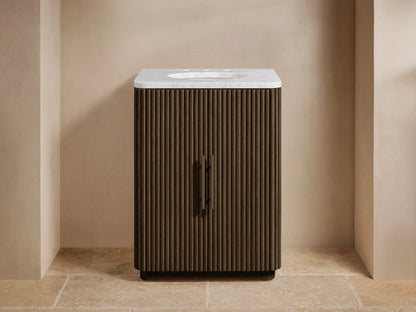 Front view of Finnley Powder Vanity with fluted dark wood, white marble top, bronzed faucet & handles, and soap/bottle.