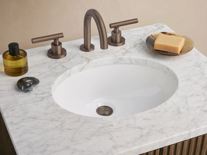 Finnley Powder Vanity: dark brown fluted wood cabinet, white marble top with oval sink, on tiled floor against beige walls.