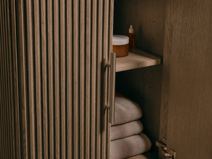 Close-up of Finnley Powder Vanity: white Carrara marble top with oval ceramic undermount sink & 3 faucet holes. Fluted dark wood base.