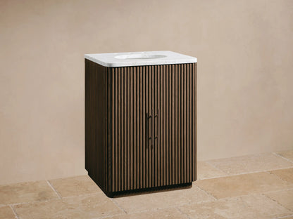 Fluted dark oak Finnley Powder Vanity with white marble top, oval sink, and dark faucet against a beige wall.