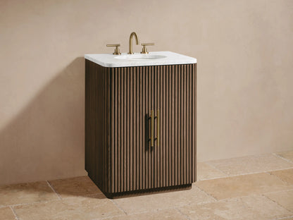 Close-up of Finnley Powder Vanity's open cabinet door with vertical fluting & brass pull, revealing shelf with toiletries & stacked towels.