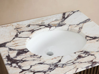 Finnley Powder Vanity with white and purple veined marble top, oval sink, brass faucet, flowers, soap dispenser, and bath salts.