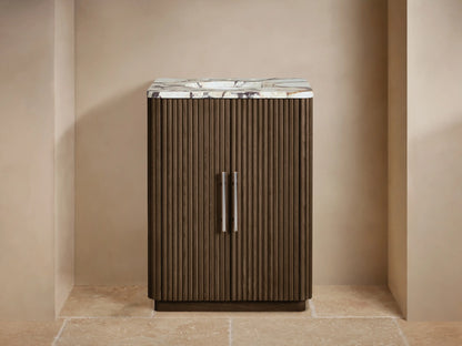 Finnley Powder Vanity with dark fluted wood cabinet, white marble top, polished nickel faucet, and a vase of flowers.