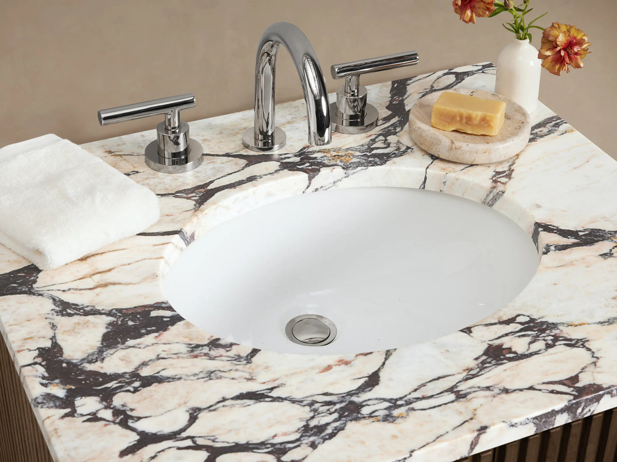 Finnley Powder Vanity, dark brown fluted wood cabinet with white marble top, oval sink, and chrome widespread faucet.