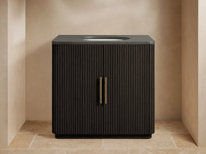 Finnley Single Vanity with dark wood slatted doors, brass handles, and a stone top with sink; accessories on top.