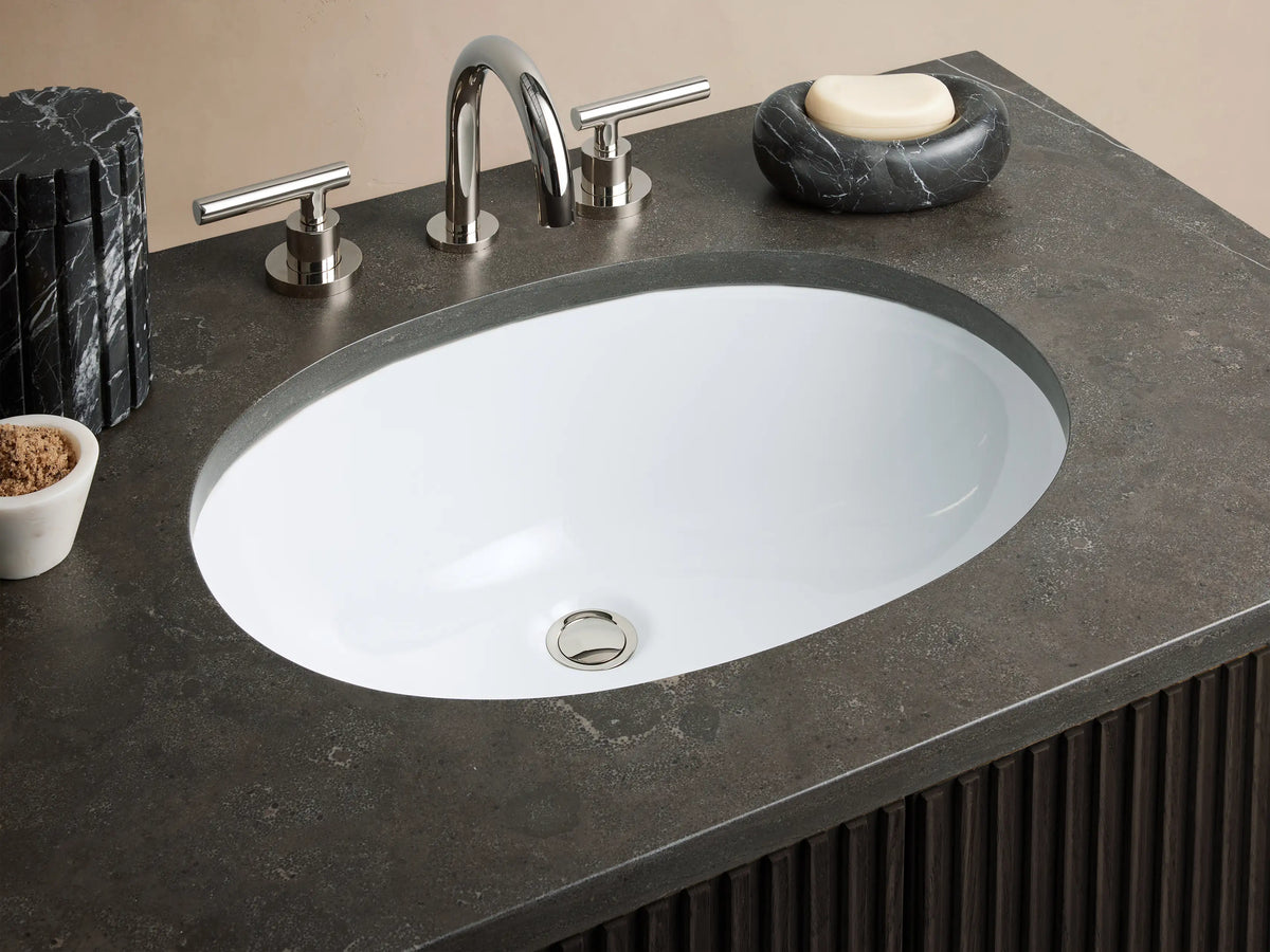 Finnley Single Vanity with dark wood finish, vertical grooves, stone top, and oval ceramic sink. Two metal handles on cabinet doors.