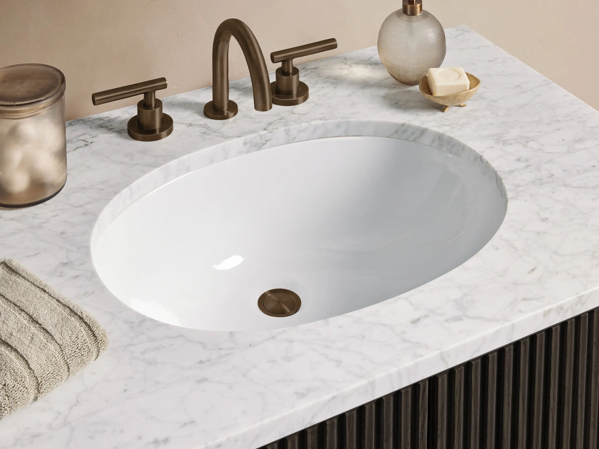 Finnley Single Vanity: Dark fluted cabinet with white marble top & oval sink, brass handles, in a neutral bathroom.