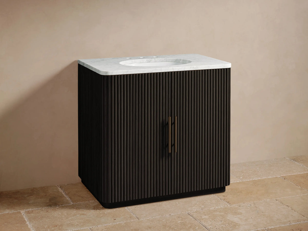 Finnley Single Vanity: dark fluted wood cabinet with white marble top, oval sink, and bronze faucet on a tiled floor.