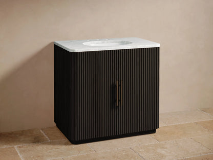 Finnley Single Vanity: dark fluted wood cabinet with white marble top, oval sink, and bronze faucet on a tiled floor.