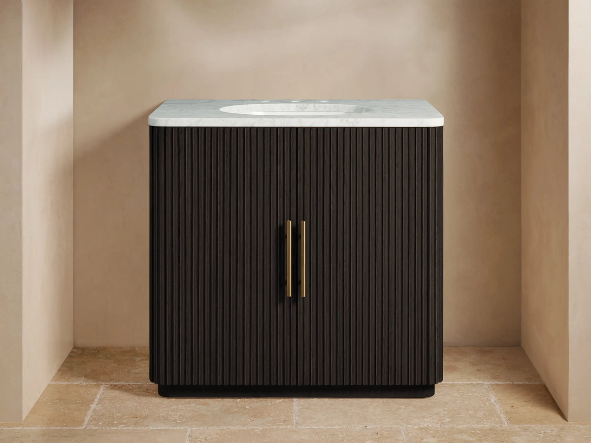 Finnley Single Vanity with dark oak wood finish, ribbed texture, marble countertop, oval ceramic sink, and brass hardware.