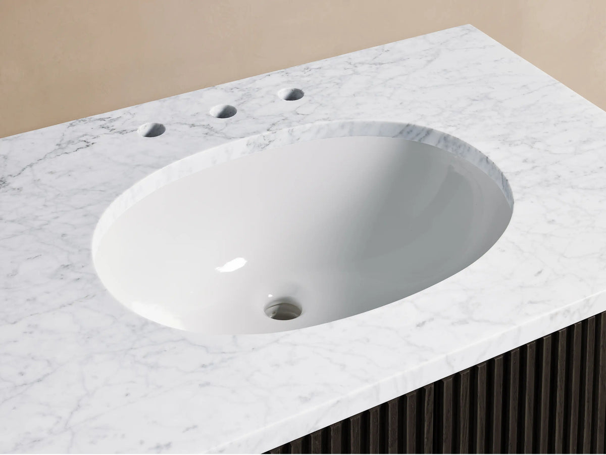Finnley Single Vanity with black ribbed front, dual vertical handles, and a white marble top with oval sink on beige background.