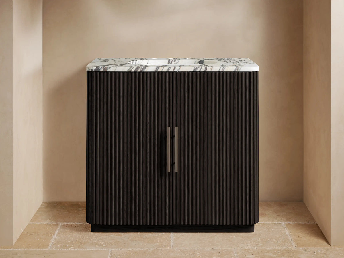 Finnley Single Vanity with a white marble top, gray veining, dark fluted wood cabinet, and a dark metal faucet in a modern bathroom.
