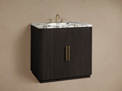 Close-up of Finnley Single Vanity with fluted dark wood door, white marble top, gold handle. Open cabinet shows stone tray, towels.