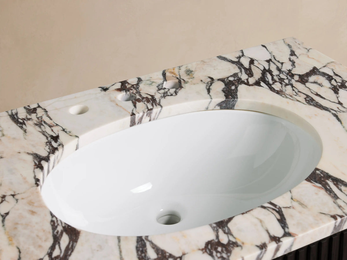 Close-up of Finnley Single Vanity with white oval sink, chrome widespread faucet on Calacatta Viola marble, towel, and vase.