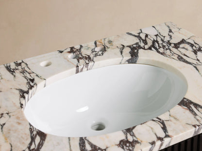 Close-up of Finnley Single Vanity with white oval sink, chrome widespread faucet on Calacatta Viola marble, towel, and vase.