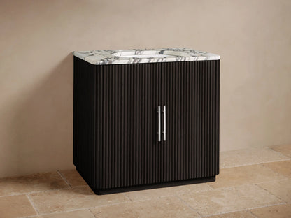 Finnley Single Vanity: black fluted cabinet, white marble top with chrome faucet & vertical pulls, against beige wall.