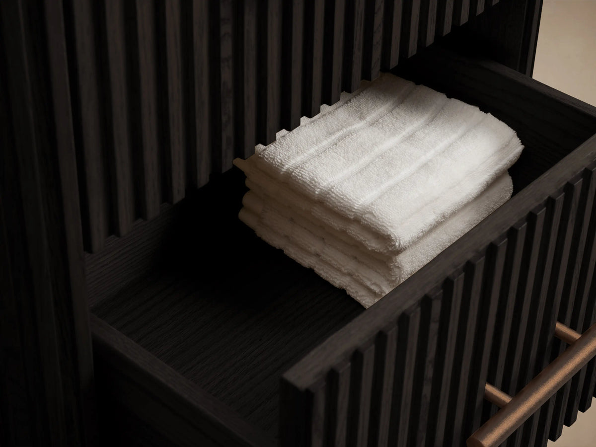 White marble top with rounded edge on dark fluted Finnley Short Bath Cabinet, featuring an antique bronze pull.