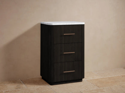 Close-up of Finnley Short Bath Cabinet, dark wood with fluted design. Open drawer holds white towels, a bronze handle is visible.