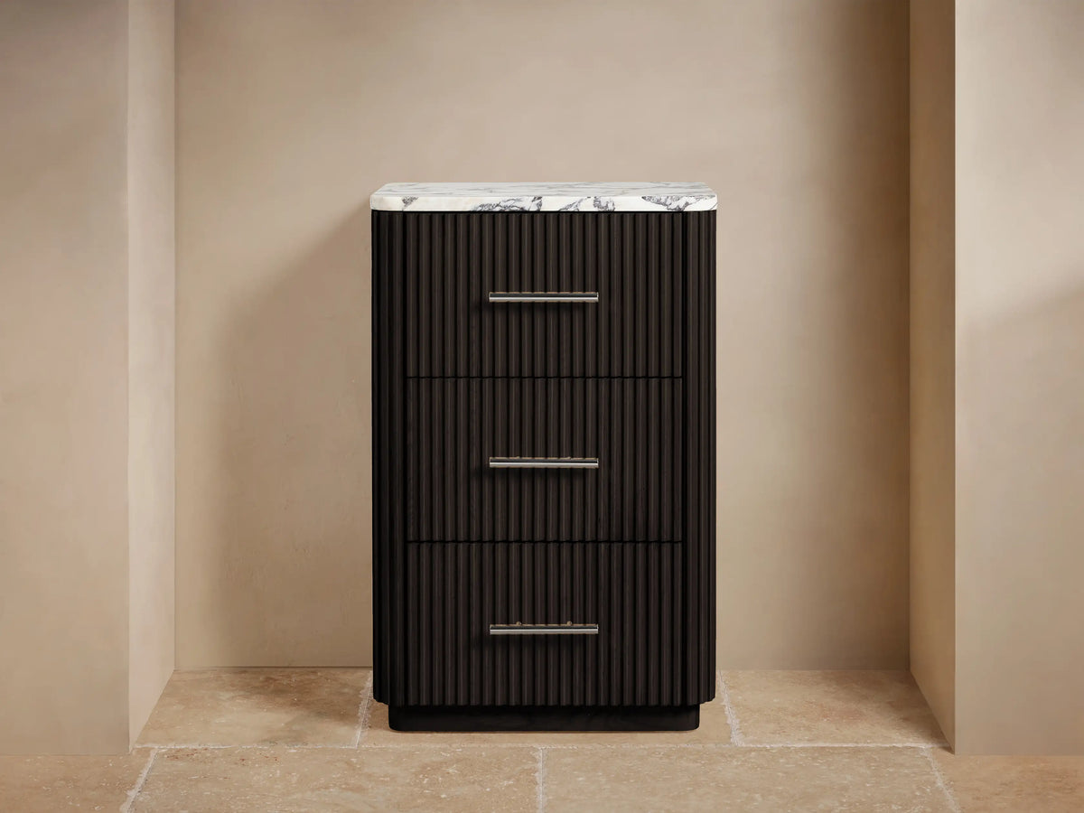 Finnley Short Bath Cabinet: Dark brown fluted design, white marble top, 3 drawers with polished nickel handles, in a calm room.