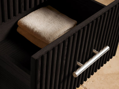Finnley Short Bath Cabinet: dark fluted wood, 3 drawers with polished nickel pulls, white Carrara marble top on a tiled floor.