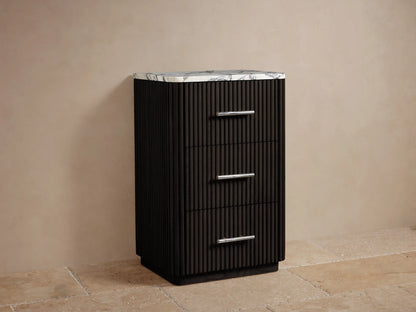 Angled close-up of Finnley Short Bath Cabinet. Honed white marble top with dark veining on dark fluted wood body with polished nickel handle.