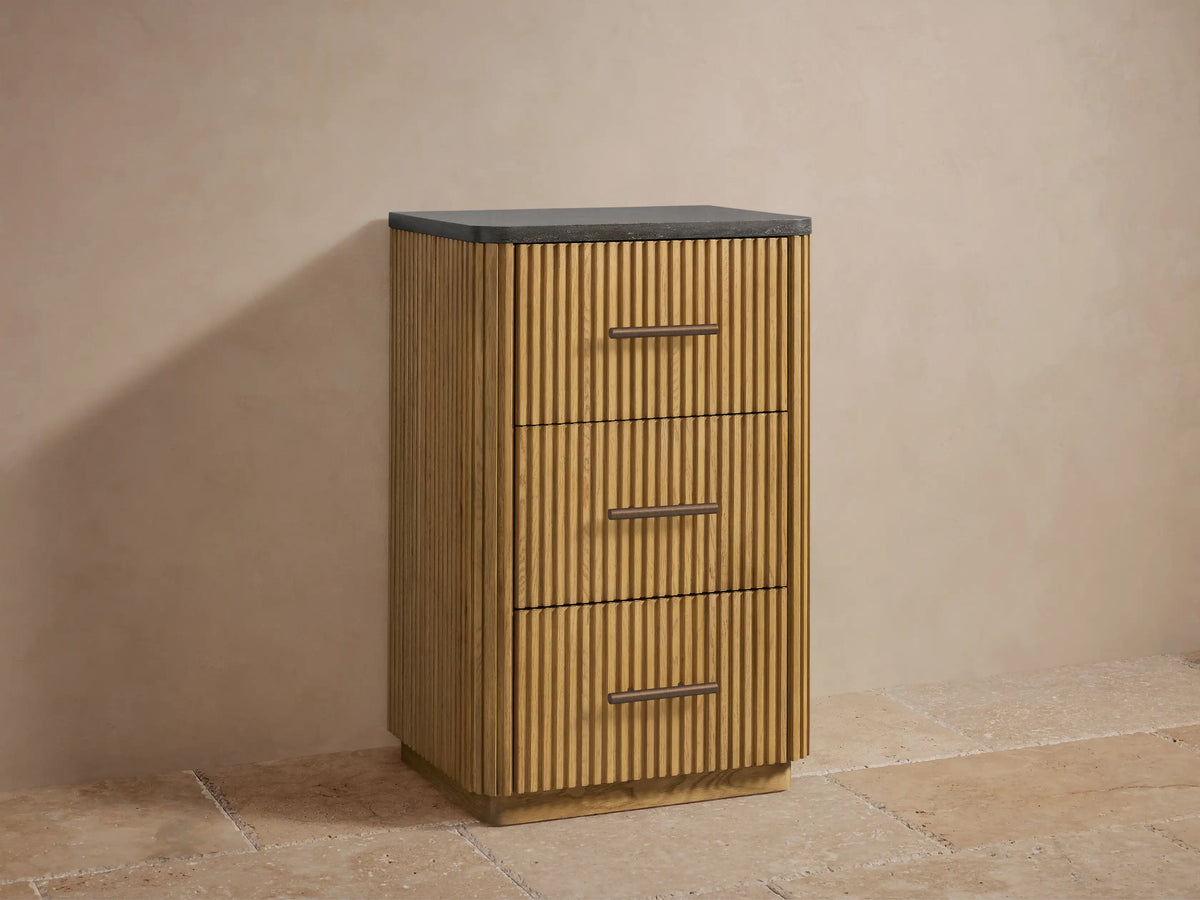 Open drawer of a Finnley Short Bath Cabinet in light oak, featuring ribbed panels, with neatly stacked white towels inside.