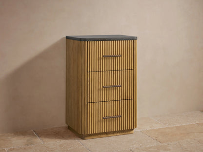 Open drawer of a Finnley Short Bath Cabinet in light oak, featuring ribbed panels, with neatly stacked white towels inside.