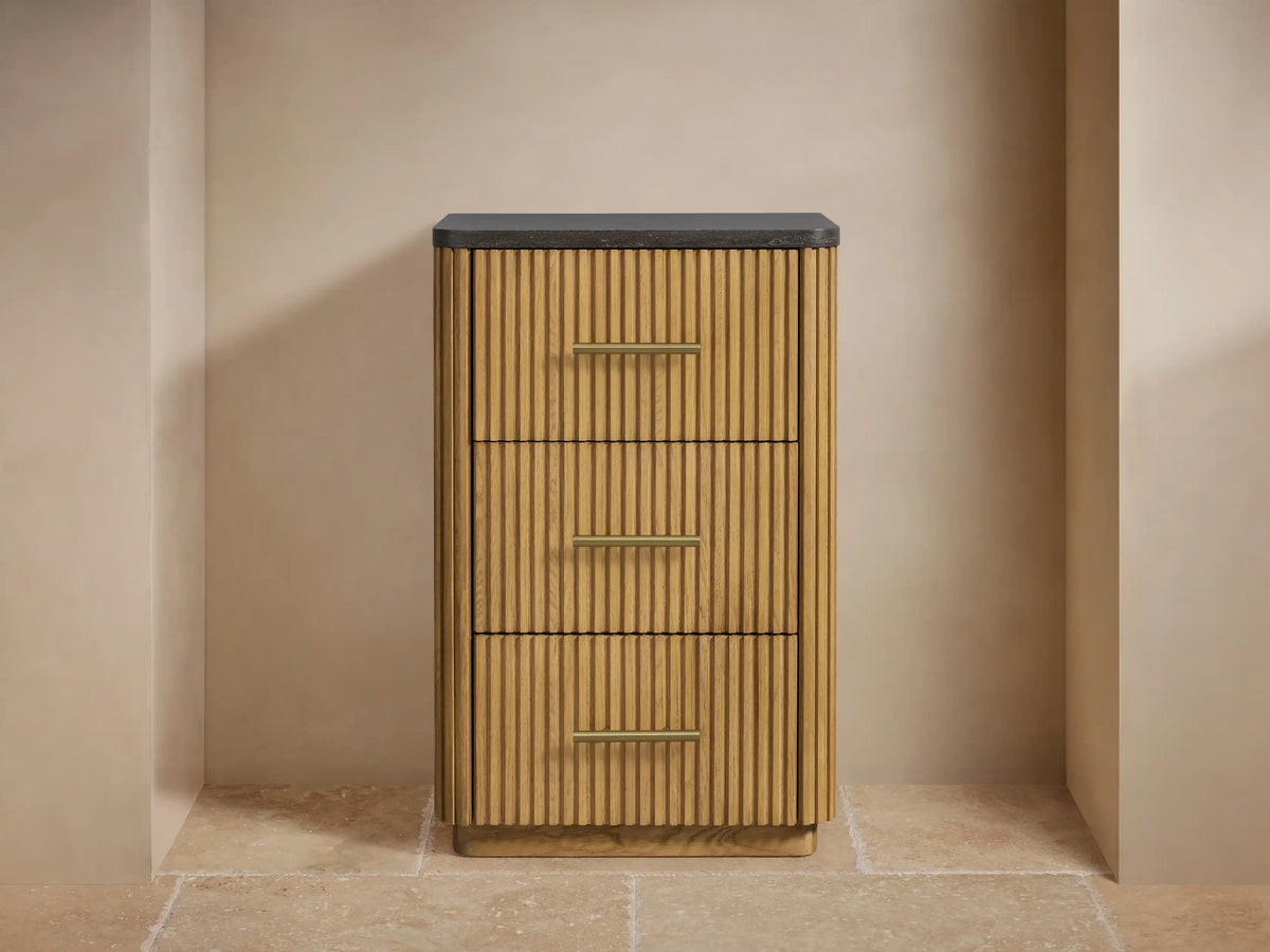 Finnley Short Etagere corner featuring oak wood with vertical grooves, a thick dark stone top, and an antique brass handle.