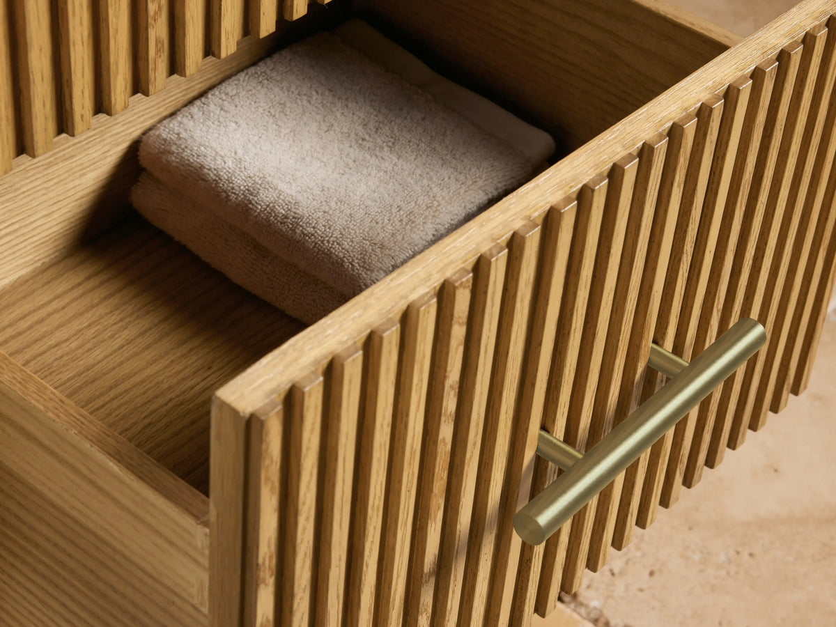 Finnley Short Bath Cabinet: White marble top with dark veining, light ribbed wood cabinet, and a dark bronze pull.