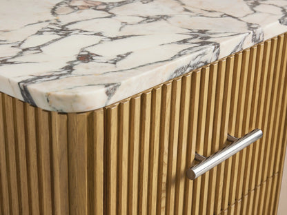 Finnley Short Bath Cabinet: Light oak fluted wood, 3 drawers with polished nickel pulls, and white marble top, against a beige wall.
