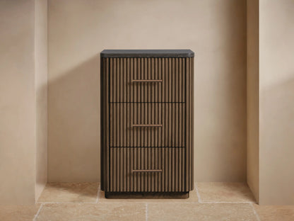 Finnley Short Bath Cabinet: Dark brown fluted oak, three drawers with bronze pulls, black stone top. Towels & vase on top.