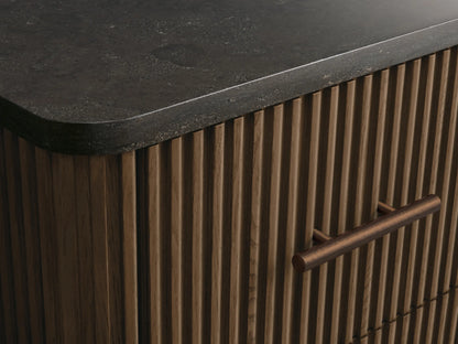 Finnley Short Bath Cabinet. Dark fluted wood with 3 drawers, antique brass pulls, and a contrasting dark stone top.