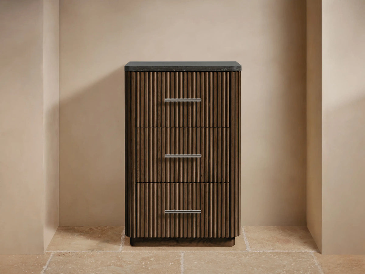 Dark oak Finnley Short Bath Cabinet with vertical fluting, 3 drawers, polished nickel handles & dark stone top. Styled with towels & vase.