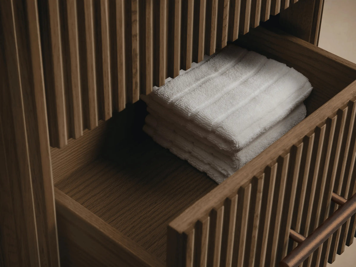 Close-up of Finnley Short Bath Cabinet: white marble top, dark oak with ribbed texture, and an antique bronze pull.