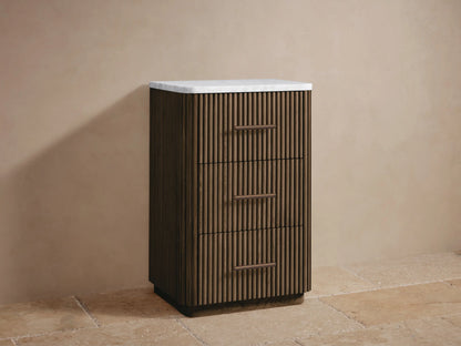 Open drawer of Finnley Short Bath Cabinet in warm oak with vertical fluting, holding folded white towels. Bronze handle on right.