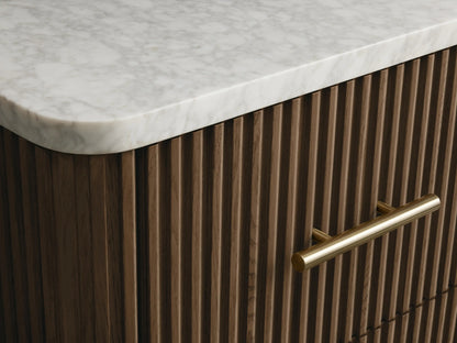 Close-up of open Finnley Short Bath Cabinet's oak drawer with fluted detailing, holding a stack of white towels. Brass handle.