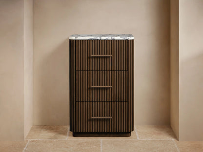 Finnley Short Bath Cabinet, dark brown fluted wood, white marble top, 3 drawers with bronze handles. Towels & decor on top.