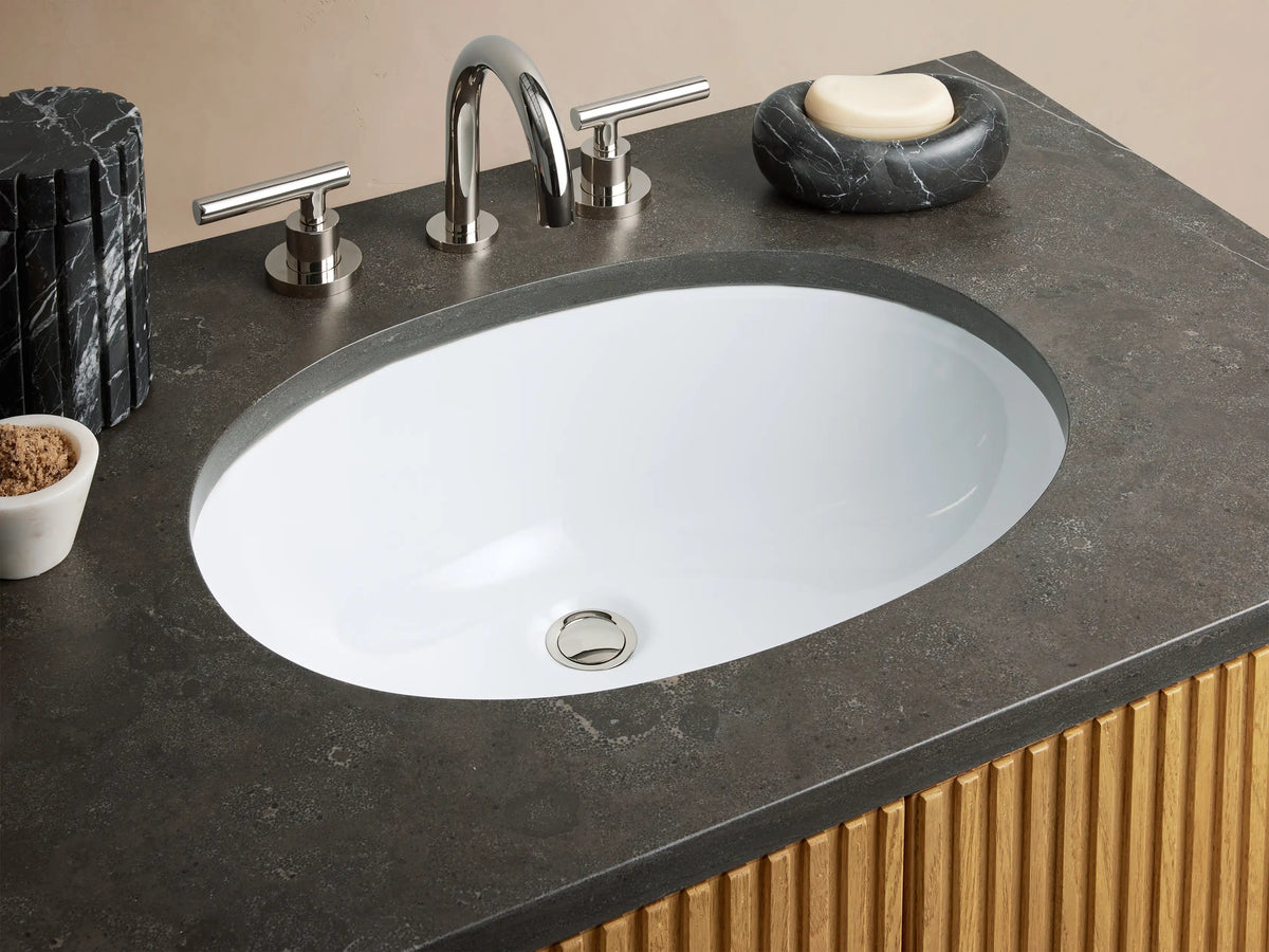 Finnley Single Vanity with vertical slatted oak wood doors, black stone top, and silver hardware in a beige tiled bathroom setting.