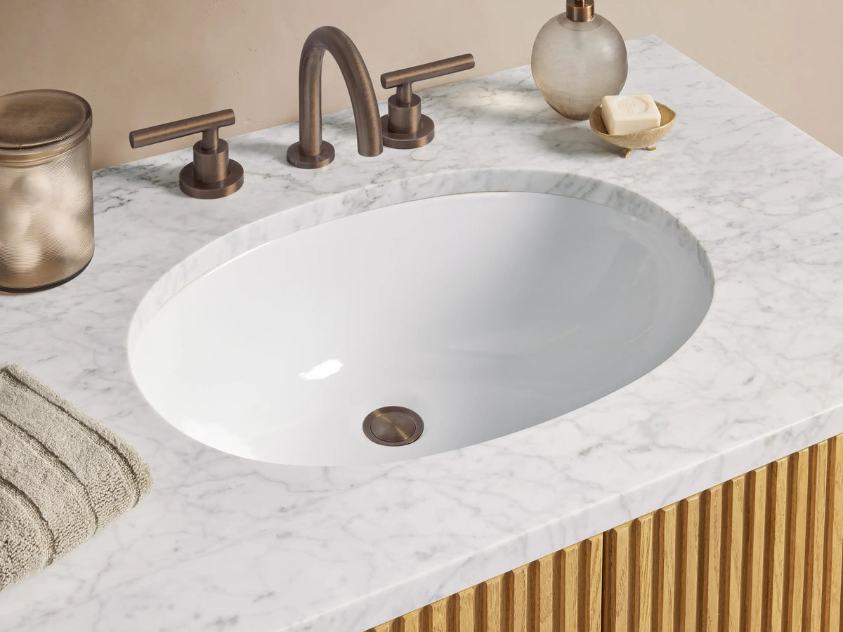 Light oak fluted Finnley Single Vanity with white Carrara marble top, oval ceramic sink, and two vertical bronze pull handles.
