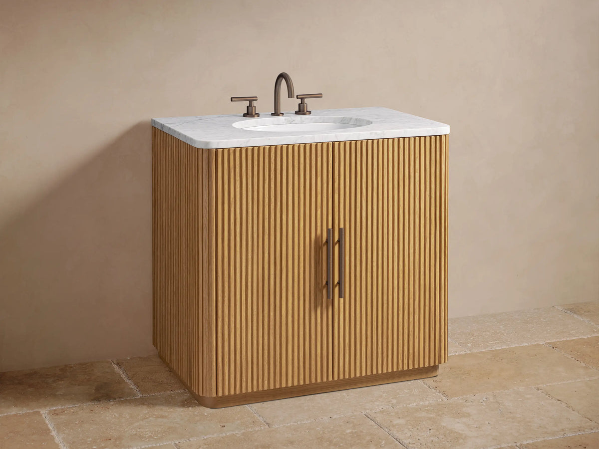 Close-up of Finnley Single Vanity's ribbed oak cabinet door slightly open, showing interior shelf with bath items and folded towels.