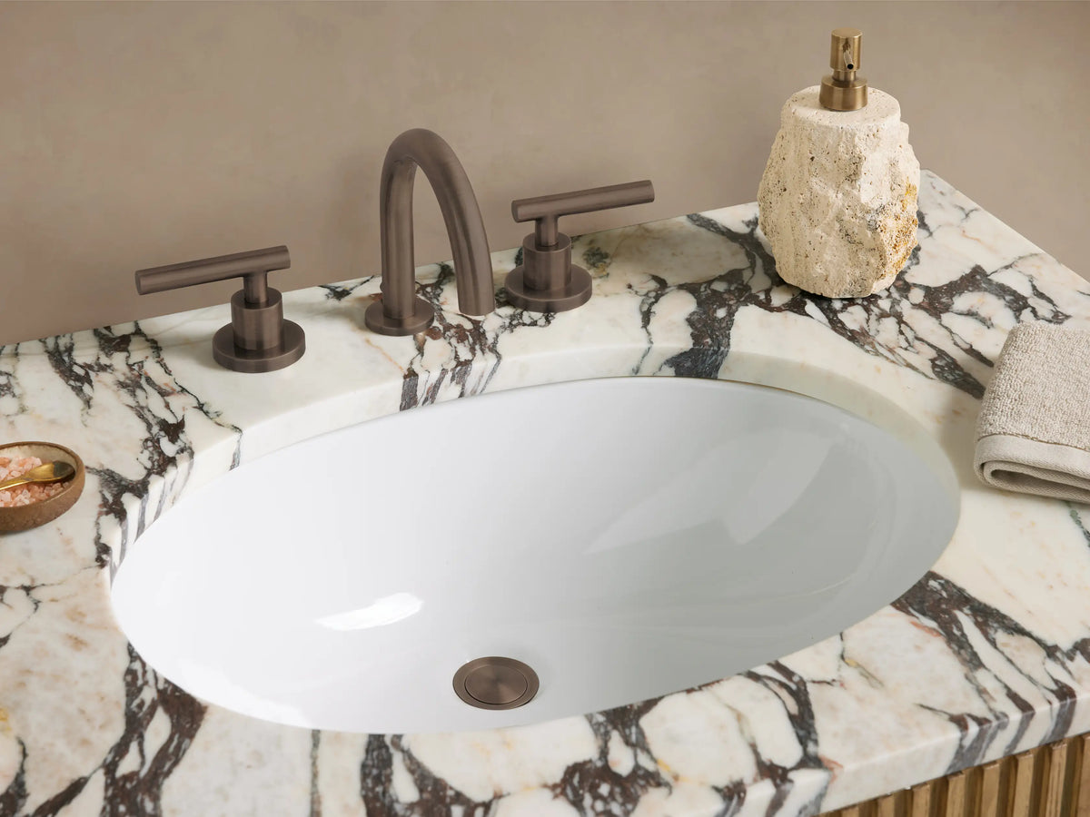 Finnley Single Vanity. Light oak fluted wood, white marble top with gray veining, oval sink, and dark metal handles.