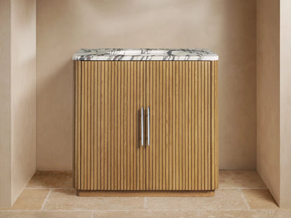 Front view of Finnley Single Vanity: light oak fluted cabinet, white veined marble top, chrome faucet in modern bathroom.