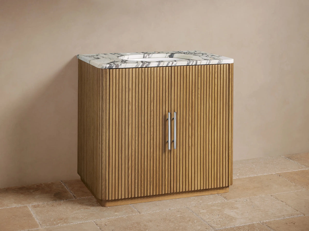 Finnley Single Vanity: Front view of fluted oak cabinet, white marble top with sink, & polished nickel faucet on tiled floor.
