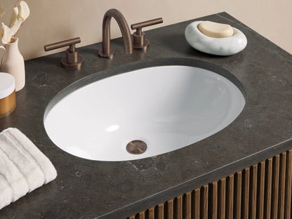 Finnley Single Vanity with dark wood fluted doors, a dark bluestone countertop, and a white oval undermount sink.