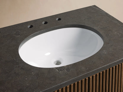 Finnley Single Vanity, close-up. Dark bluestone top with white oval sink, antique brass faucet, and slatted oak wood cabinet front.